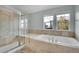 Bright bathroom features a glass-enclosed shower and separate tub, illuminated by natural light from the windows at 7949 S Blackstone Pkwy, Aurora, CO 80016