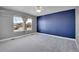Comfortable bedroom boasts a striking navy accent wall, neutral carpet, and two windows with outdoor views at 7949 S Blackstone Pkwy, Aurora, CO 80016