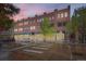 Street view of brick condominium building with large storefront windows and rooftop terraces against a colorful evening sky at 4144 Tennyson St # 10, Denver, CO 80212