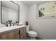 Bathroom features a sleek black framed mirror, single sink vanity and toilet next to a window at 9408 Harvard Dr, Highlands Ranch, CO 80130