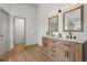 Modern bathroom features dual sinks, wood cabinets, and bright lighting with a doorway to a laundry closet at 9408 Harvard Dr, Highlands Ranch, CO 80130