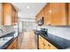 Bright galley kitchen featuring stainless steel appliances, light hardwood floors, and black countertops at 1632 S Josephine St, Denver, CO 80210