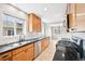 Bright galley kitchen with stainless steel appliances, light hardwood floors, and black countertops at 1632 S Josephine St, Denver, CO 80210