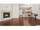 Open-concept living room with hardwood floors, fireplace, and kitchen with bar seating at 15945 E Geddes Dr # 54, Aurora, CO 80016