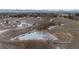 Aerial view of expansive vacant land with small pond and mountain views in the distance at 5747 S Lowell Blvd, Littleton, CO 80123