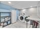 This laundry room features a blue accent wall, washer, dryer, shelving and storage at 10869 W 65Th Way, Arvada, CO 80004