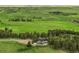 Aerial view of a home nestled amongst trees on vast acreage of rolling green hills and pastures at 1752 Private Road 130, Elizabeth, CO 80107
