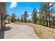A large concrete patio and pine trees highlight the back yard at 1752 Private Road 130, Elizabeth, CO 80107