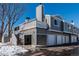 Exterior view of a multi-story townhome with garages and a snow-covered yard at 1180 S Monaco Pkwy # 3, Denver, CO 80224