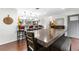 Open-concept dining area with hardwood floors, bar seating, and a large rustic table under bright lighting at 7132 Xavier Way, Westminster, CO 80030