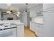 Bright kitchen with white cabinets, hardwood floors, and a view into the living area at 3026 S Alton Ct, Denver, CO 80231