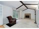 Bright living room featuring vaulted ceilings with exposed beams and a classic brick fireplace at 3026 S Alton Ct, Denver, CO 80231