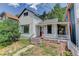 Charming home with a red front door and a cozy porch, nestled amidst lush greenery and a bright sky backdrop at 1324 Virginia St, Idaho Springs, CO 80452