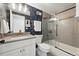 Stylish bathroom with shower-tub combo, floral wallpaper, and vanity with a light countertop and gold hardware at 6830 Lamar St, Arvada, CO 80003