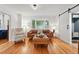 Cozy living room featuring hardwood floors, a bay window, and a sliding barn door at 6830 Lamar St, Arvada, CO 80003