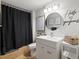 Modern bathroom with vanity, round mirror, stylish light fixture, and a shower with black patterned curtain at 5342 S Halifax Cir, Centennial, CO 80015