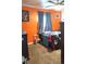Bedroom featuring an orange accent wall, brown carpet, and dark blue curtains over the window at 1242 S Seneca Way, Denver, CO 80223