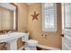 Charming powder room features a pedestal sink, decorative star, and a window for natural light at 8726 Gardenia Cir, Arvada, CO 80005