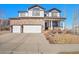 Charming two-story home with a stone facade, white siding, and a three-car garage at 8726 Gardenia Cir, Arvada, CO 80005