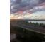 Beautiful sunset view overlooking the lake with lush greenery, a serene road, and soft horizon with hills under colorful clouds at 2617 Channel Dr, Highlands Ranch, CO 80129