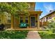 Charming stone-clad home with a covered front porch featuring a cozy blue bench and lush landscaping at 557 S Clarkson St, Denver, CO 80209