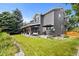 A spacious backyard featuring a covered patio, lush lawn, rock border, and mature trees at 6772 Tiger Tooth, Littleton, CO 80124