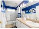 Bright bathroom featuring a double vanity, wainscoting, and a shower/tub combo at 6772 Tiger Tooth, Littleton, CO 80124