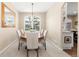 Sunlit dining room features a round table, six chairs, chandelier, and a large window with plantation shutters at 6772 Tiger Tooth, Littleton, CO 80124