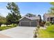Two-story home boasts a three-car garage, manicured lawn, and landscaping featuring trees, plants, and flowers at 6772 Tiger Tooth, Littleton, CO 80124