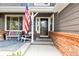 Charming front porch with stylish seating, American flag, and brick accents at 6772 Tiger Tooth, Littleton, CO 80124
