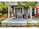 Inviting front porch is staged with white chairs, a cushioned bench, patterned area rug, and decorative planters at 6772 Tiger Tooth, Littleton, CO 80124