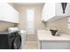Functional laundry room with modern appliances, built-in cabinets, a sink, and natural light at 6772 Tiger Tooth, Littleton, CO 80124
