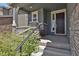 Inviting front porch featuring stone columns and a stylish dark-colored front door with sidelight window at 24555 E Ohio Dr, Aurora, CO 80018