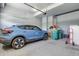 Spacious garage featuring a blue car and green trash bins at 24555 E Ohio Dr, Aurora, CO 80018