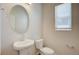 Well-lit half bath with a pedestal sink, oval mirror and window at 12225 W 57Th Pl, Arvada, CO 80002