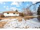 Large backyard with snowy patches and a view of the house's exterior and covered patio at 2784 E Maplewood Ave, Centennial, CO 80121