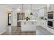 Modern white kitchen with stainless steel appliances, a center island with a white countertop, and open access to living area at 2784 E Maplewood Ave, Centennial, CO 80121