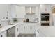 Modern kitchen featuring white cabinets, stainless steel appliances, stylish backsplash, and a sleek white countertop at 2784 E Maplewood Ave, Centennial, CO 80121