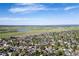 Expansive aerial view of a community with lush greenery, a serene lake, and a distant skyline at 4290 S Deframe St, Morrison, CO 80465