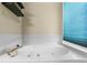 Relaxing bathroom featuring a jetted tub with white tile surround and a window with privacy blinds at 4290 S Deframe St, Morrison, CO 80465