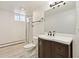 Well-lit bathroom with tiled floor, vanity with dark wood cabinets and curved sink, shower with glass doors at 2172 S Harlan St, Denver, CO 80227