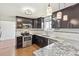 This kitchen features espresso cabinets, stainless steel appliances, granite countertops, and wood floors at 2172 S Harlan St, Denver, CO 80227