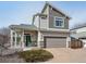 Two-story home featuring stone accents, a covered porch, a two-car garage, and a well-maintained landscape at 18066 E 104Th Way, Commerce City, CO 80022