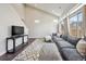 Open-concept living area featuring hardwood floors, a gray sofa, large windows, and a modern media center at 18066 E 104Th Way, Commerce City, CO 80022