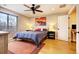 Bright bedroom featuring hardwood floors, a bed with a blue duvet, and an adjacent hallway creating an inviting space at 2471 S High St, Denver, CO 80210