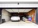 View of an open garage featuring a white SUV, concrete walls, and an assortment of household items at 2471 S High St, Denver, CO 80210