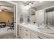 Bathroom with double sinks, white cabinets, and views into a connected bedroom at 907 Greenridge Ln, Castle Pines, CO 80108
