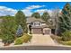 Beautiful two-story home with a three-car garage and manicured front lawn, surrounded by mature trees at 907 Greenridge Ln, Castle Pines, CO 80108