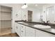 Bathroom featuring dual sinks, white cabinets, dark countertops, and walk in closet at 26322 E 2Nd Ave, Aurora, CO 80018