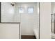Walk in shower with subway tile, a built-in bench, dark tile flooring, and two windows at 26322 E 2Nd Ave, Aurora, CO 80018